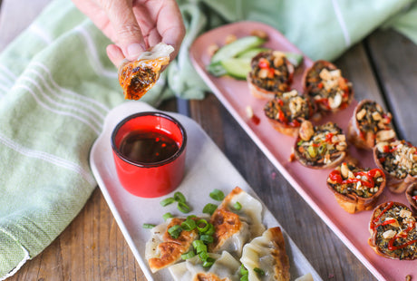 Platter shot with a dumpling being dipped in sauce